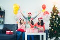 Group of young friends sitting next to a nicely decorated Christmas tree, exchanging Christmas presents. friends laughing and Royalty Free Stock Photo