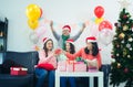 Group of young friends sitting next to a nicely decorated Christmas tree, exchanging Christmas presents. friends laughing and Royalty Free Stock Photo