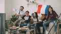 Group of young friends sports fans with French national flags watching sport championship on TV together cheering up Royalty Free Stock Photo