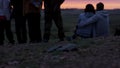 Group of young friends standing together and looking at sunset. Rear view of young people admiring a view. Group of