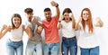 Group of young friends standing together over isolated background angry and mad raising fists frustrated and furious while Royalty Free Stock Photo