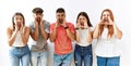 Group of young friends standing together over isolated background shouting angry out loud with hands over mouth Royalty Free Stock Photo