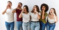 Group of young friends standing together over isolated background shouting and screaming loud to side with hand on mouth Royalty Free Stock Photo
