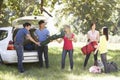 Group Of Young Friends Unloading Camping Equipment From Trunk Of