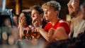 Group of Young Friends Watching a Live Soccer Match on TV in a Sports Bar. Excited Fans Cheering and Royalty Free Stock Photo