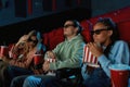A group of young friends wearing glasses, looking emotional while watching movie together in cinema auditorium Royalty Free Stock Photo