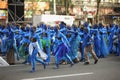 Group of young girls and boys coloured in blue like Avatar preparing for a march in the middle of the street