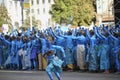 Group of young girls and boys coloured in blue like Avatars standing in the middle of the street and waving hands.