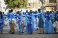 Group of young girls and boys coloured in blue like Avatars standing in the middle of the street and waving hands.