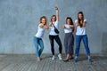 Group of young girls are posing against the wall smiling and showing gestures with their hands. Gray background, save Royalty Free Stock Photo