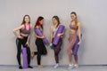 Group of young girls stand with yoga mats near the wall wearing sportswear waiting for the start of yoga or stretching