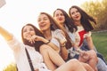 Group of young happy carefree girls friends making selfie on summer city street, sunset time background