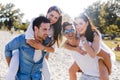 Group of young happy people carrying women on a sandy beach