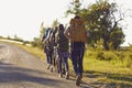 Group of young hikers walk in a row along the road with backpacks on their shoulders.