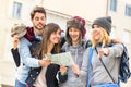 Group of young hipster tourists friends cheering with city map