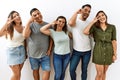 Group of young hispanic friends standing together over isolated background doing peace symbol with fingers over face, smiling Royalty Free Stock Photo