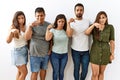 Group of young hispanic friends standing together over isolated background pointing down looking sad and upset, indicating Royalty Free Stock Photo
