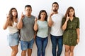 Group of young hispanic friends standing together over isolated background pointing up looking sad and upset, indicating direction Royalty Free Stock Photo