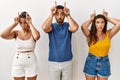 Group of young hispanic people standing over isolated background doing funny gesture with finger over head as bull horns Royalty Free Stock Photo