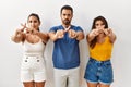 Group of young hispanic people standing over isolated background rejection expression crossing fingers doing negative sign Royalty Free Stock Photo