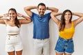 Group of young hispanic people standing over isolated background relaxing and stretching, arms and hands behind head and neck Royalty Free Stock Photo