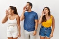 Group of young hispanic people standing over isolated background shouting and screaming loud to side with hand on mouth Royalty Free Stock Photo