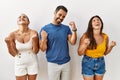 Group of young hispanic people standing over isolated background very happy and excited doing winner gesture with arms raised, Royalty Free Stock Photo