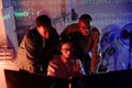 Group of young intercultural programmers bending in front of computer monitors