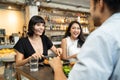 Group of young interracial best friend people sitting indoor restaurant eating food together for lunch. Women talking to Asian man Royalty Free Stock Photo