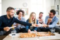 Group of young businesspeople with pizza having lunch in a modern office. Royalty Free Stock Photo