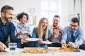 Group of young businesspeople with pizza having lunch in a modern office. Royalty Free Stock Photo