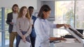 Group of young managers standing in queue for copier at office Royalty Free Stock Photo