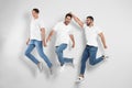 Group of young men in stylish jeans jumping near wall Royalty Free Stock Photo