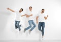 Group of young men in stylish jeans jumping near wall Royalty Free Stock Photo