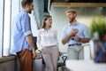 Group of young modern people in smart casual wear having a brainstorm meeting while standing in the creative office.