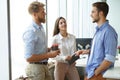 Group of young modern people in smart casual wear having a brainstorm meeting while standing in the creative office.