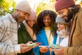 Group of young multi-ethnic friends using cell phones outdoors. People addicted to technology. Royalty Free Stock Photo