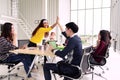 Group of young multiethnic diverse people gesture hand high five, laughing and smiling together in brainstorm meeting at office.