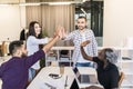 Group of young multiethnic diverse people gesture hand high five, laughing and smiling together in brainstorm meeting at office.