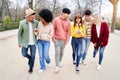 Group of young multiracial friends using mobile phones and walking in a park. Cheerful People having fun Royalty Free Stock Photo