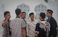 A group of young Muslim Asian men in beautiful shirts are standing near the walls of the mosque