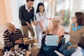 A group of young and old people in a retirement home give an elderly woman a mobile phone. Royalty Free Stock Photo