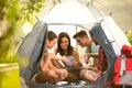 Group of young people on camping trip in countryside sitting in tent