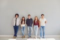 Group of young people in casual clothes smiling while standing against gray background. Royalty Free Stock Photo