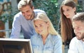 Group of young people in casual wear sitting at the office desk and discussing something while looking at PC together. Royalty Free Stock Photo