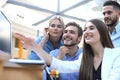 Group of young people in casual wear sitting at the office desk and discussing something while looking at PC together. Royalty Free Stock Photo