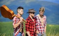 Group of young people in checkered shirts walking together on top of mountain. Men with guitar hiking on sunny day