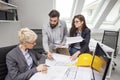 Three cooworkers with plans on table Royalty Free Stock Photo