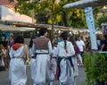 Group of young people dressed in religious clothes of pilgrims or priests walking through a market of the popular festival of