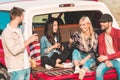 group of young people drinking beer and chatting while sitting in car trunk Royalty Free Stock Photo